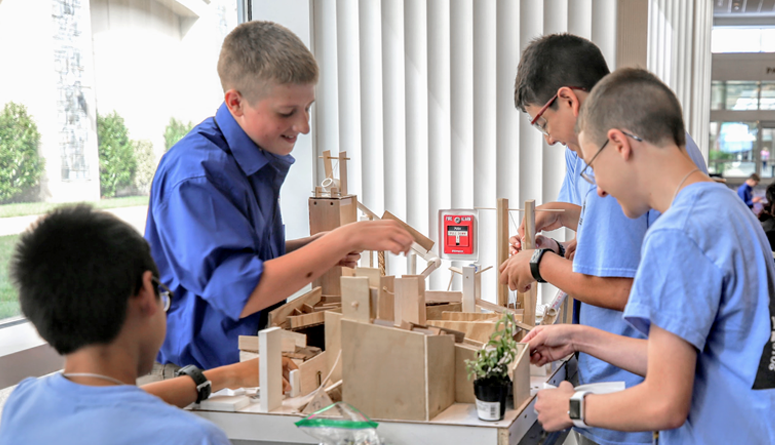 Four boys working on a wood-construction project together.